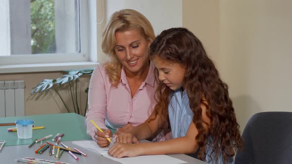 Mature Female Teacher Enjoying Working with Her Little Student at School