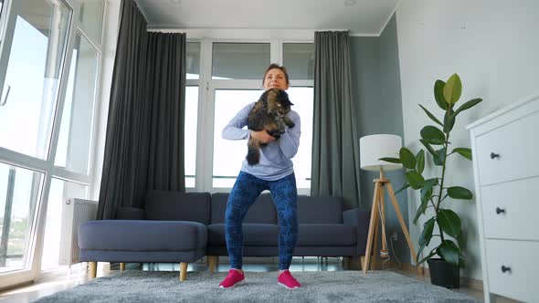 Woman Squats with a Cat in Her Arms