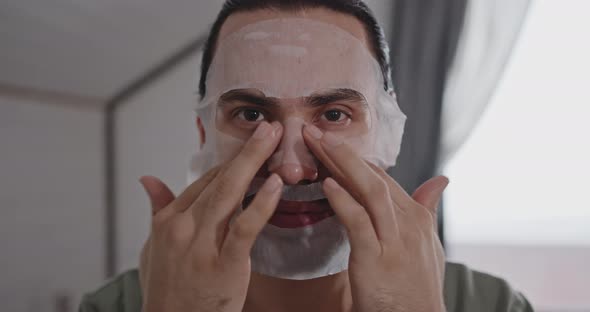 Portrait of a Young Man Using a Fabric Moisturizing Face Mask at Home