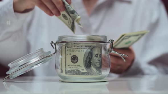 The Lady Puts Dollars in a Transparent Jar