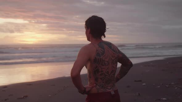 Young Man Doing Somersault on Beach at Sunset