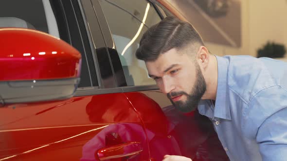 Cheerful Man Smiling to the Camera While Examining Car at the Dealership