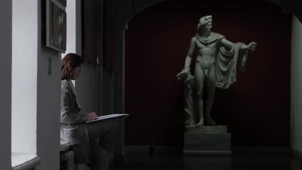 A Young Girl Artist Draws an Antique Sculpture of a Man in the Corridor of the University Sitting on alt