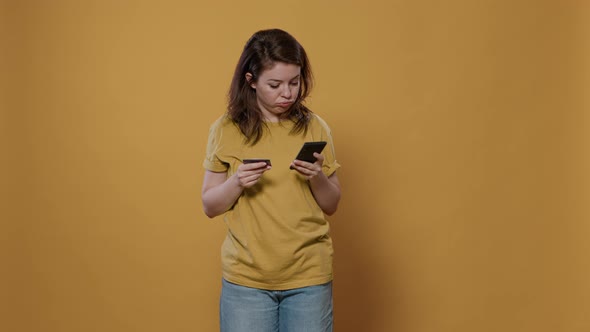 Bored Woman Doing Online Shopping Holding Smartphone Having Trouble Typing Credit Card