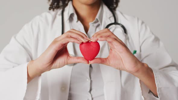 Video of biracial female doctor holding heart on white background
