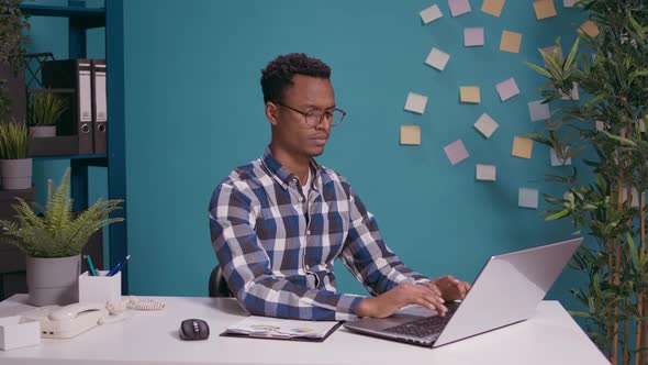 Sales Specialist Doing Thumbs Down Gesture in Front of Laptop Screen