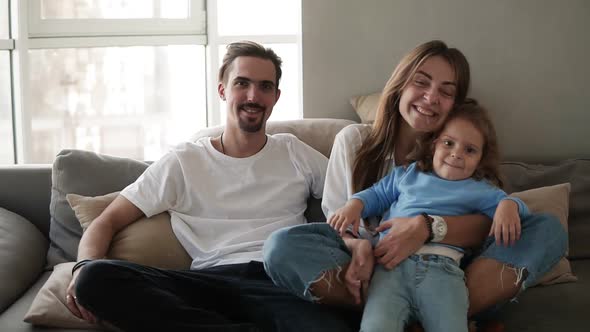 Portrait of Happy Caucasian Family Sitting Embraced on Sofa in Living Room in Slow Motion