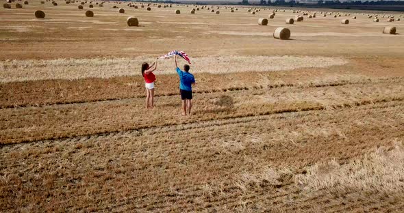 A Young Happy Couple Runs Carefree and Jumps on a Wheat Field