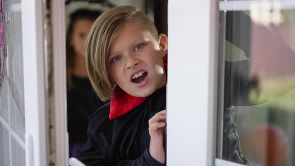 Blurred Girl in Costume Standing Indoors As Boy Appearing Scaring Looking at Camera Grimacing