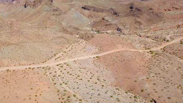 Aerial view following a desert dirt road, in sunny Kingman wash, USA - pan, drone shot