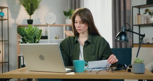 Female Worker Sitting at Her Workplace at Home Office and Working with Financial Report