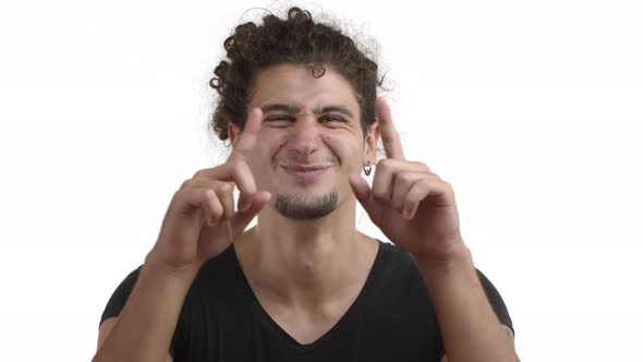 Closeup of Attractive Caucasian Guy in Black Tshirt with Earrings and Curly Ponytail Shaping Heart