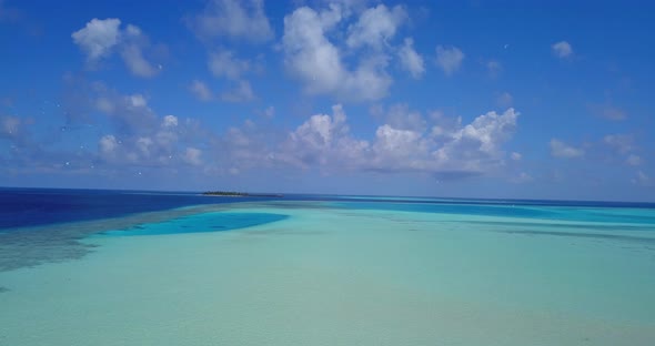 Luxury overhead travel shot of a white sandy paradise beach and aqua blue water background in 4K