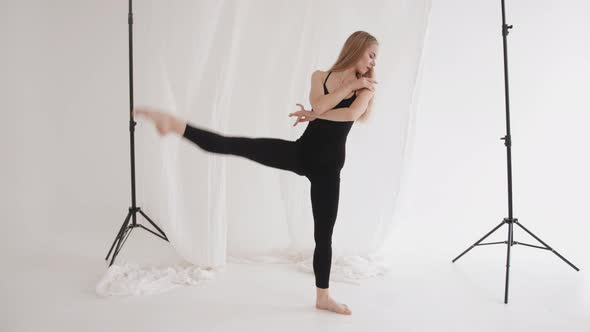 An Elegant Young Girl is Engaged in Stretching and Demonstrates Elements of Classical Dance Against