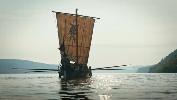 Medieval Ship with Vikings on Board Sails in the Middle of the River