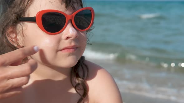 Little girl apply sunscreen. 