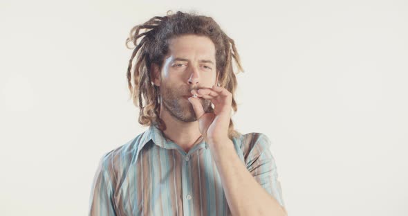 Man with dreadlocks smoking medicinal marijuana on white background