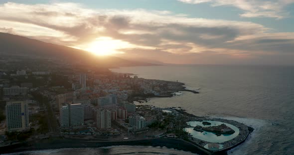 Aerial Panorama of Puerto De La Cruz Resorts and Pools Surrounded By Sea Waves on Sunset Tenerife