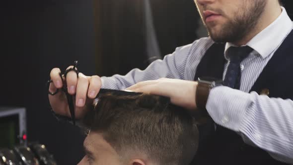 Cropepd Shot of a Professional Barber Cutting Hair of His Male Client
