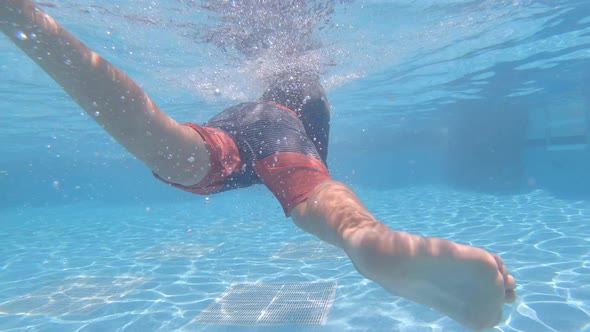 A boy plays and swims underwater in a pool at a hotel resort.