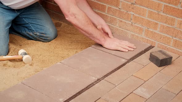 Worker Lays Tiles on the Pressed Sand
