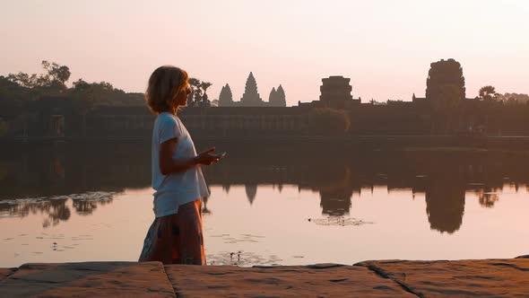 Slow motion: woman taking selfie at Angkor Wat ruins at sunrise