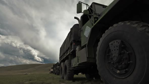 Dollying time-lapse of a stationary military convoy truck.
