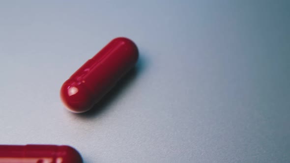 Red Medical Capsules Lie on Clean White Background