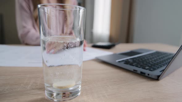 Unrecognizable Business Woman Worker at Table with Papers and Laptop in Background Throws Vitamin