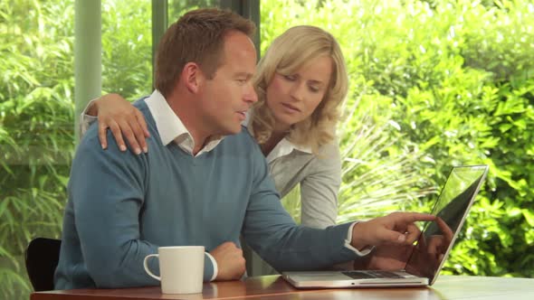 Mid Shot of male and female at dinning table looking at computer