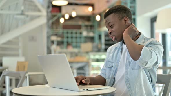 Stressed Young African Man Having Neck Pain in Cafe