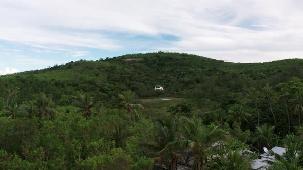 Helicopter hovers above helipad on remote tropical island in Fiji, aerial shot