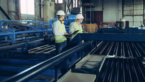 Two Engineers Are Watching the Conveyor with Metal Tile