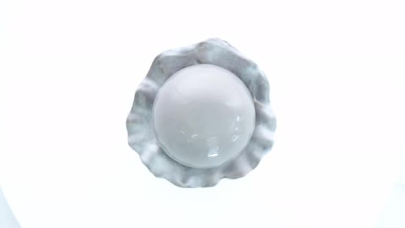 Dessert in the Form of Pearl with Gray Glaze Spinning on White Background