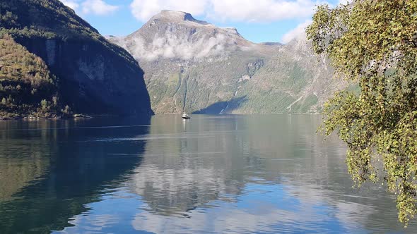 Tranquil, calm water surface of the Geiranger Fjord. Ferry in the distance