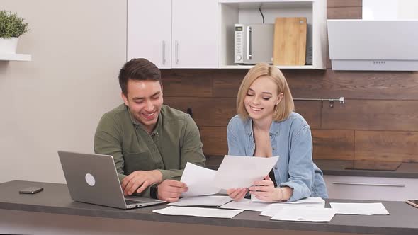 Beautiful Young Husband Discussing Contract Details of Financial Issues with Smiling Happy Wife