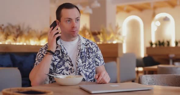 Busy Man Eating Pasta in a Cafe and Talks By Phone at the Same Time