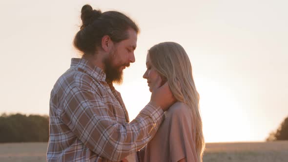 Loving Husband Bearded Man Strokes Face of Woman Beloved Girl and Hugging Close Up Sunset Background