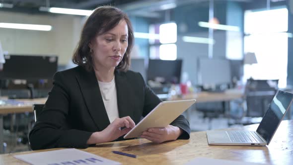 Serious Middle Aged Businesswoman Working on Tablet in Office