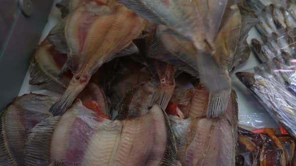 Hand Shows Dried Salted Flatfish on Counter in Seafood Market