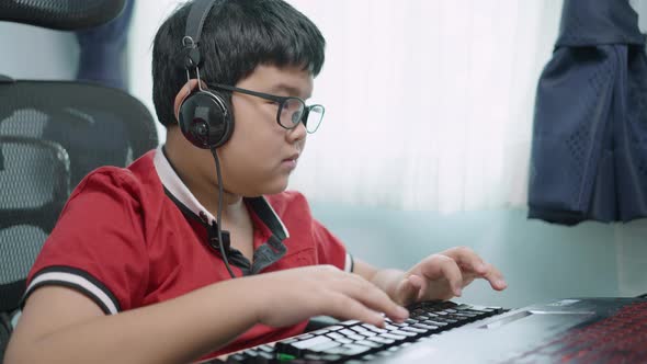Asian boy typing on laptop in a room