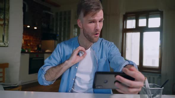 Young Guy Hipster Having Video Call Using Smartphone at Table During Selfisolation at Home Spbas