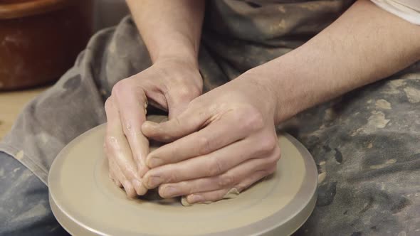 The Hands of a Potter Make a Jug on a Potter's Wheel