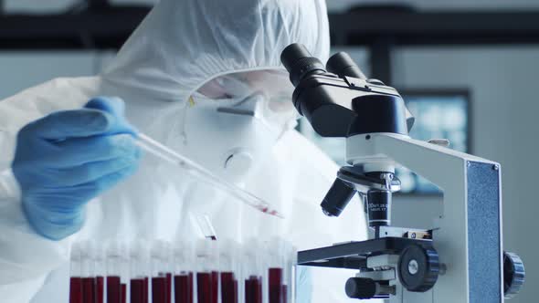 Scientist in protection suit and masks working in research lab using laboratory equipment.