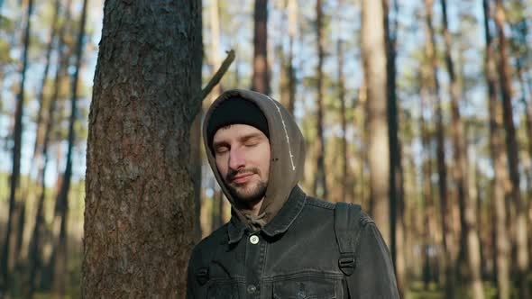 a Man Stands Near a Tree in the Forest and Smiles at the Camera