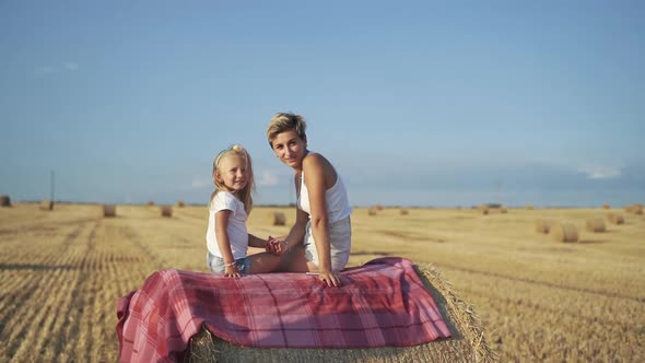 Happy Family Having Talk on a Haycock on a Sunny Day in Field