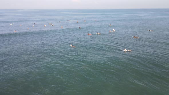 Aerial view of people surfing on waves with surfboards when vacation in Bali, Indonesia .