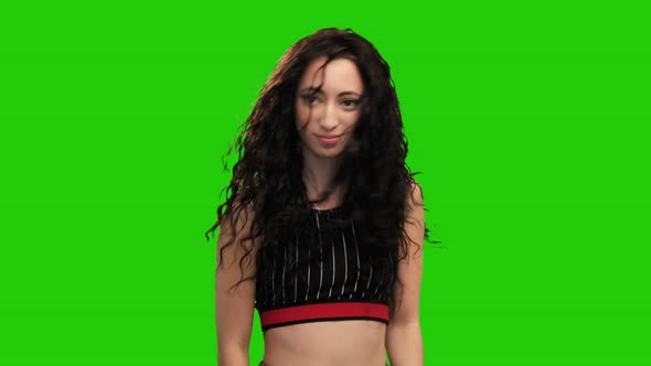 Portrait of long haired brunette girl in crop top dancing on green screen