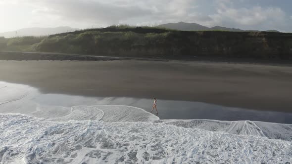 Aerial View of a woman walking on the beach, Praia do Areal, Azores, Portugal.