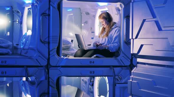 A Girl is Listening to Music in a Capsule of a Pod Hotel